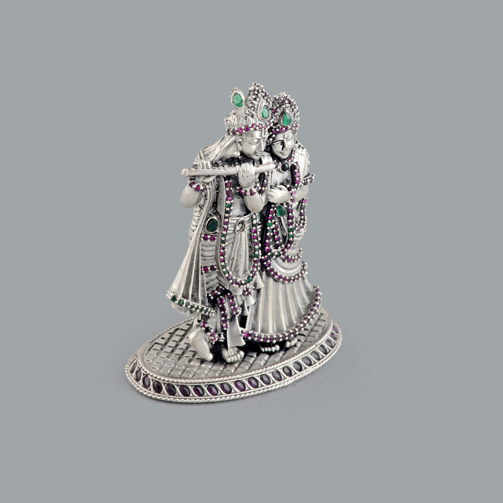 Silver Radha Krishna gleaming with ruby and emerald grace.